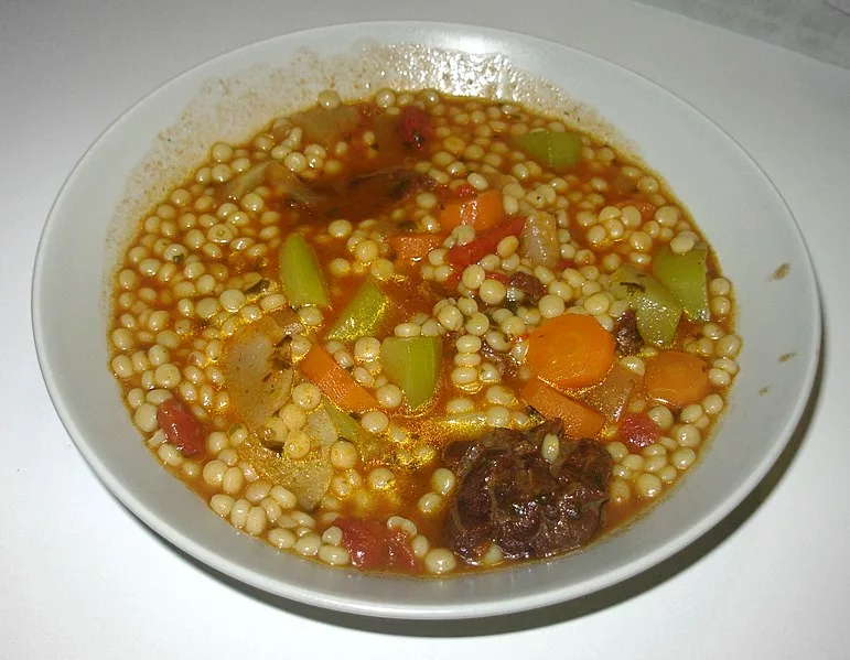 Photographie d'un plat de berkoukes algérien aux légumes et à la viande